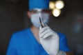 Professional surgeon in blue uniform in a medical mask in sterile gloves holds a metal scalpel in his hand. Plastic doctor in the Royalty Free Stock Photo