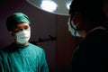 Professional surgeon doctor standing under bright light, using surgical equipment to do surgery at hospital operating room. Royalty Free Stock Photo