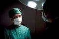 Professional surgeon doctor standing under bright light, using surgical equipment to do surgery at hospital operating room. Royalty Free Stock Photo