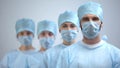 Professional surgeon team in mask and uniform looking at camera, hospital work