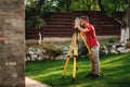 professional surveyor working with total station theodolite on landscaping project