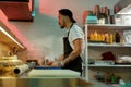 Professional sushi chef looking busy while adding ingredients, spreading them over nori sheet, making delicious rolls at Royalty Free Stock Photo