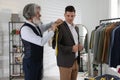 Professional tailor measuring shoulder seam length on client`s jacket in atelier Royalty Free Stock Photo