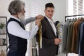 Professional tailor measuring shoulder seam length on client`s jacket in atelier Royalty Free Stock Photo