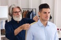 Professional tailor measuring shoulder seam length on client`s shirt in atelier Royalty Free Stock Photo
