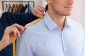 Professional tailor measuring shoulder seam length on client`s shirt in atelier, closeup Royalty Free Stock Photo