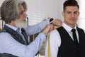 Professional tailor measuring shoulder seam length on client`s vest in atelier Royalty Free Stock Photo