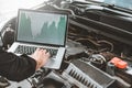 Professional Technician Hands of checking car engine repair service using laptop on car