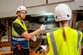 Professional technician hold light stick and discuss to his co-worker to the problem of part of electric train in workplace area