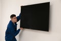 Professional technician installing modern flat screen TV on wall indoors