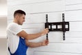 Professional technician installing TV bracket on wall indoors