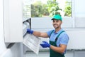 Professional technician maintaining modern air conditioner