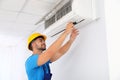 Professional technician maintaining modern air conditioner