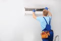 Professional technician maintaining modern air conditioner