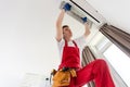 Professional technician maintaining modern air conditioner indoors.