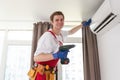 Professional technician maintaining modern air conditioner indoors.