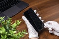 Gloved hands carefully remove a shattered tempered glass screen protector from a modern smartphone, highlighting essential device Royalty Free Stock Photo