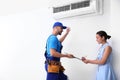 Professional technician speaking with woman about air conditioner