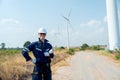 Professional technician worker man with smiling and stand with look at camera in front of wind turbine or windmill with blue sky Royalty Free Stock Photo