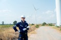 Professional technician worker man stand with hold plan paper and look forward in front of wind turbine or windmill with blue sky Royalty Free Stock Photo