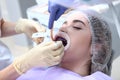 Professional teeth cleaning. The dentist applies a purple gel to the patient`s teeth before cleaning. The assistant is holding a