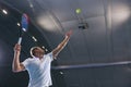 Cropped portrait of professional tennis player serving tennis ball isolated over court background. Side view