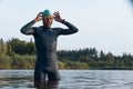 Professional triathlete before swimming in river's open water. Man wearing swim equipment practicing triathlon on the Royalty Free Stock Photo