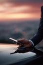 Professional using a smartphone on a sleek surface against a sunset city backdrop. Concept modern tech, connectivity, success. Royalty Free Stock Photo
