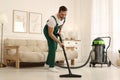 Professional janitor vacuuming floor in living room Royalty Free Stock Photo