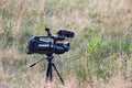 Professional video camera on tripod. Documentary filming wildlife. Filmmaking gear at meadow