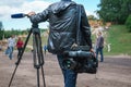 Professional video operator or videographer standing with tripod and digital camera