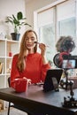 Professional vlogger. Cute and young woman using brush to apply highlighter while recording make up tutorial