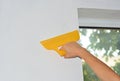 A professional wallpaper installer is wallpapering the wall around the window and removing air bubbles using a smoother tool Royalty Free Stock Photo