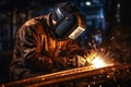 Professional welder in protective uniform and mask welding metal on the industrial table