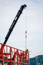 Professional welder with safety harness mounted on a crane and welding a metal structure