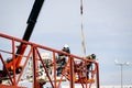 Professional welder with safety harness mounted on a crane and welding a metal structure