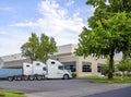 Professional white big rig bonnet semi trucks tractors standing in row on the warehouse parking lot waiting for the loaded semi Royalty Free Stock Photo