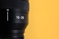 Professional wide angle photo lens with focal distance 16-35mm at yellow background with copy space