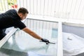 Professional window cleaner using a window cleaner squeegee to clean a large fold down apartment window