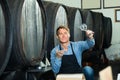 Winemaker holding glass of wine in cellar.