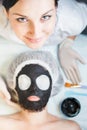 Professional woman, cosmetologist in spa salon applying mud face mask Royalty Free Stock Photo