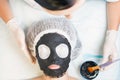 Professional woman, cosmetologist in spa salon applying mud face mask Royalty Free Stock Photo