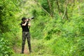 Professional woman photographer taking outdoor with prime lens in the green jungle rain forest nature.