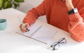 Professional woman in sweater writing notes on pad, wearing smartwatch, focused on productivity Royalty Free Stock Photo