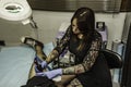Professional woman tattooer working tattoo in a man leg. High an