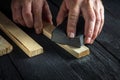 Professional woodworker cleans the wood plank with an abrasive tool. Builder hands close up. Renovation or construction idea