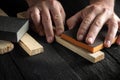 Professional woodworker cleans wood plank with an abrasive tool. Builder hands close up. Renovation or construction idea