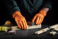 Professional woodworker cleans wooden plank with abrasive tools. Hands of the builder close-up during work. Renovation or