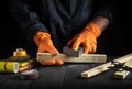 Professional woodworker cleans wooden planks with an abrasive tools. Hands of builder close-up during work. Renovation or