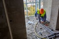 Worker or builder in workwear and safety helmet is installing plastic pipes using modern tools in a flat of building Royalty Free Stock Photo